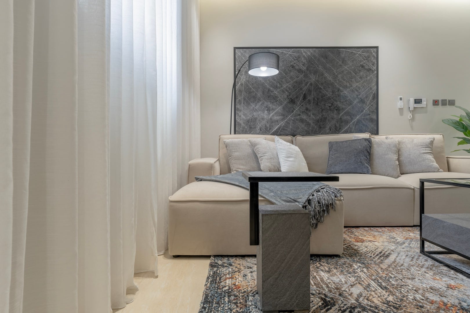 Close view of a cream sofa with grey cushions and a slim side table, Riyadh apartment