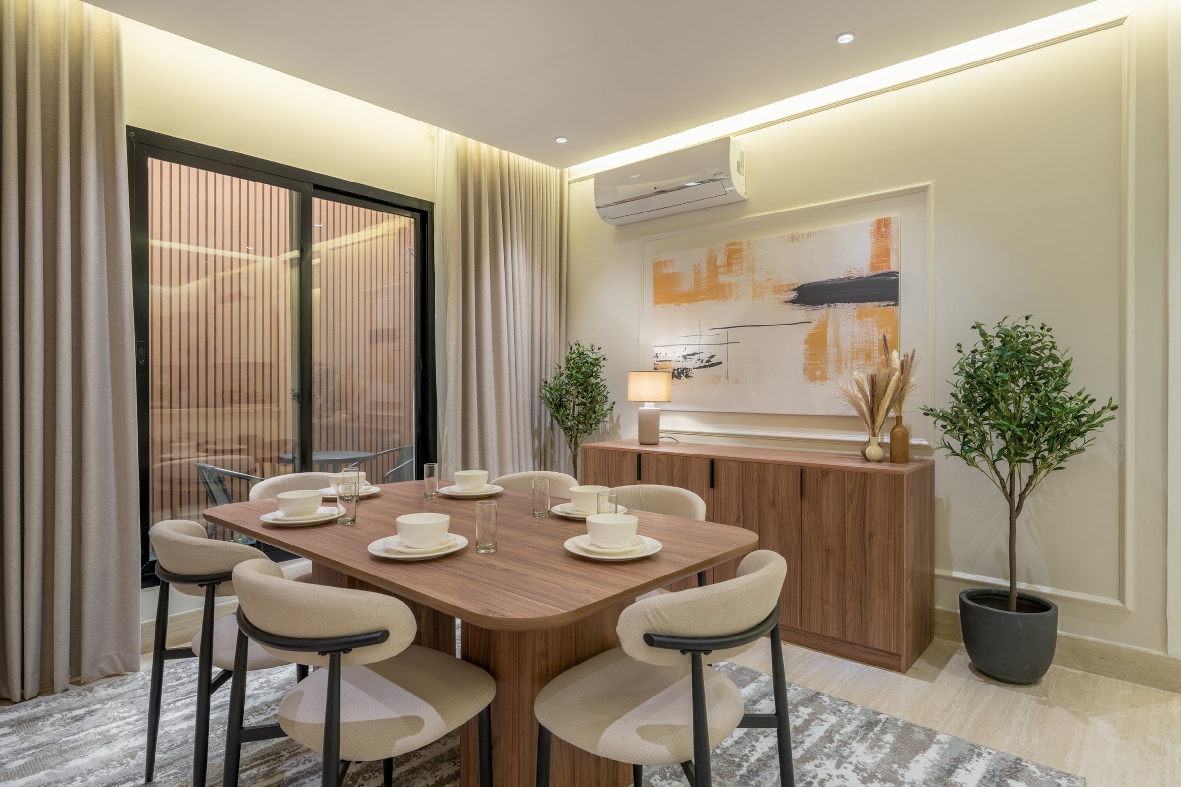 Dining table for six with curved cream chairs and a walnut sideboard, Riyadh apartment